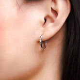 Fine jewellery, silver jewellery, hypoallergenic, tarnish-free, Close-up left view of an ear wearing a silver hoop earring with a blurred background